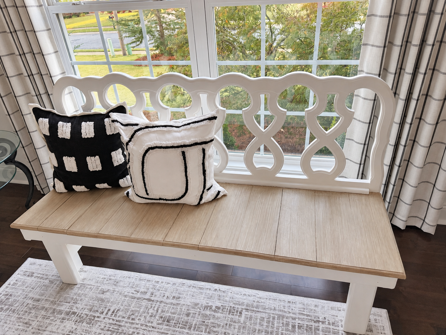 Living room bench with a lighter faux-wood seat and black-and-white pillows