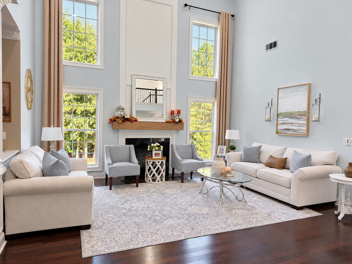 The Ivey House living room featuring a DIY wood mantel, tall windows, cream sofas, and soft blue accents