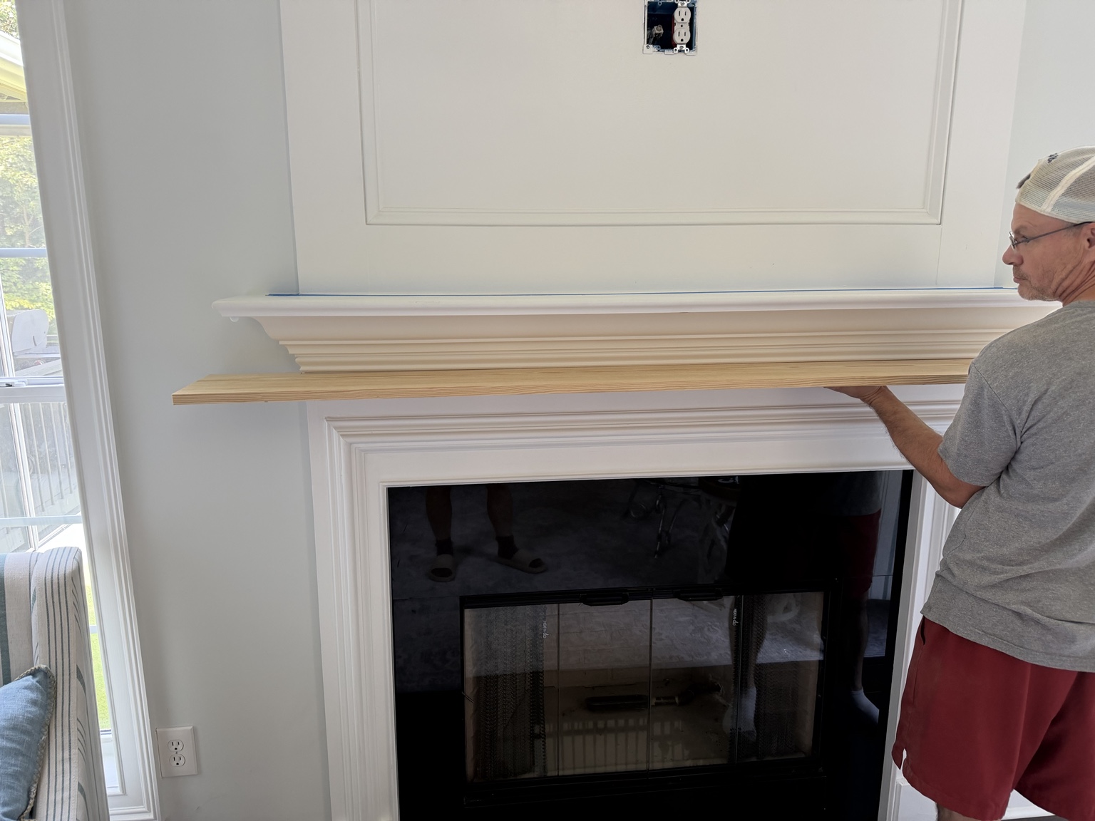 Testing the fit of the unfinished pine cover over the white mantel