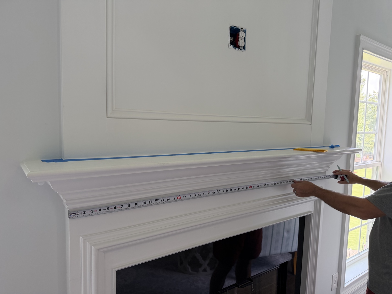 Measuring the original white mantel with a tape measure