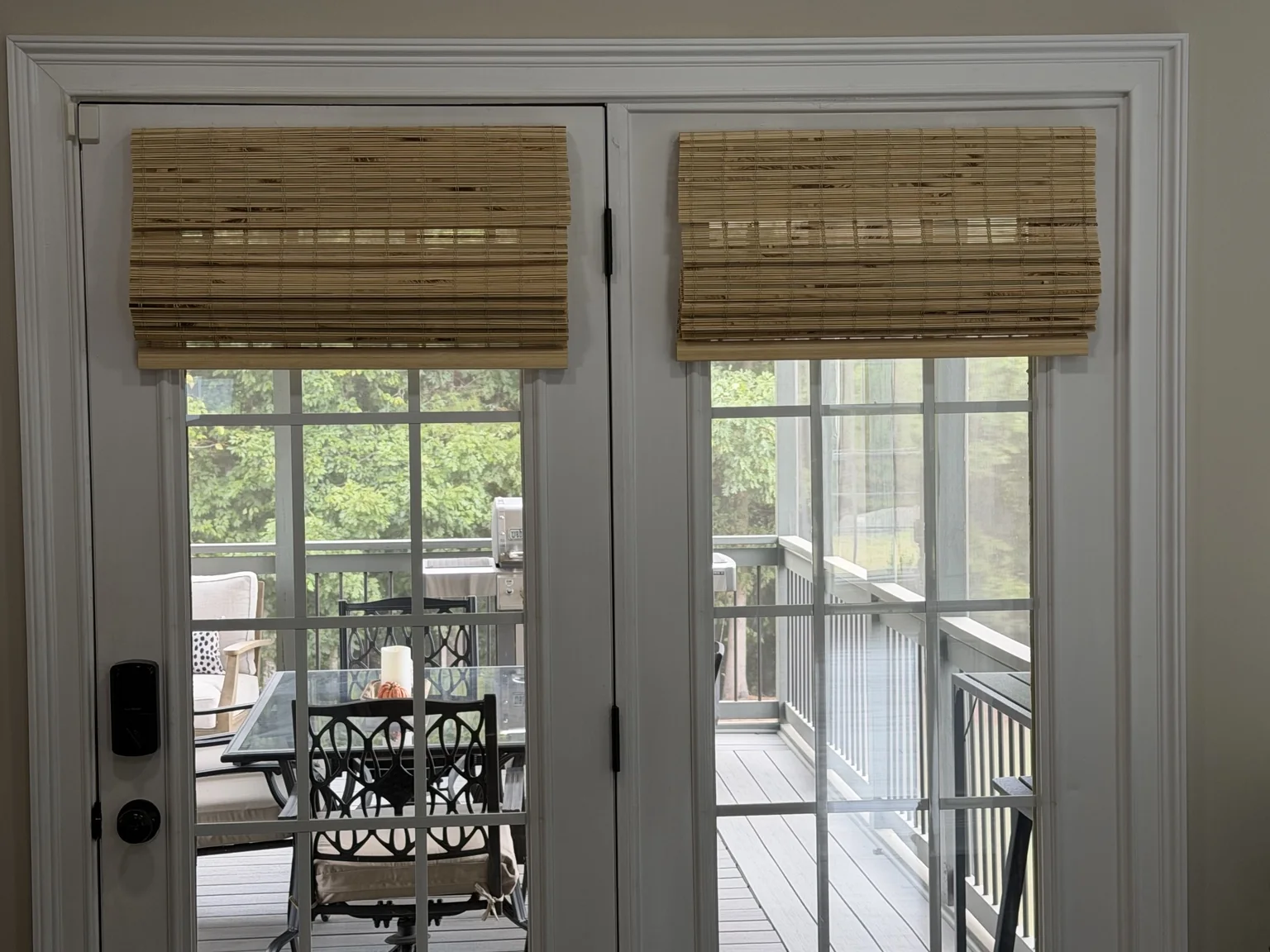 Two bamboo Roman shades mounted on the metal French doors, with no holes drilled in the doors