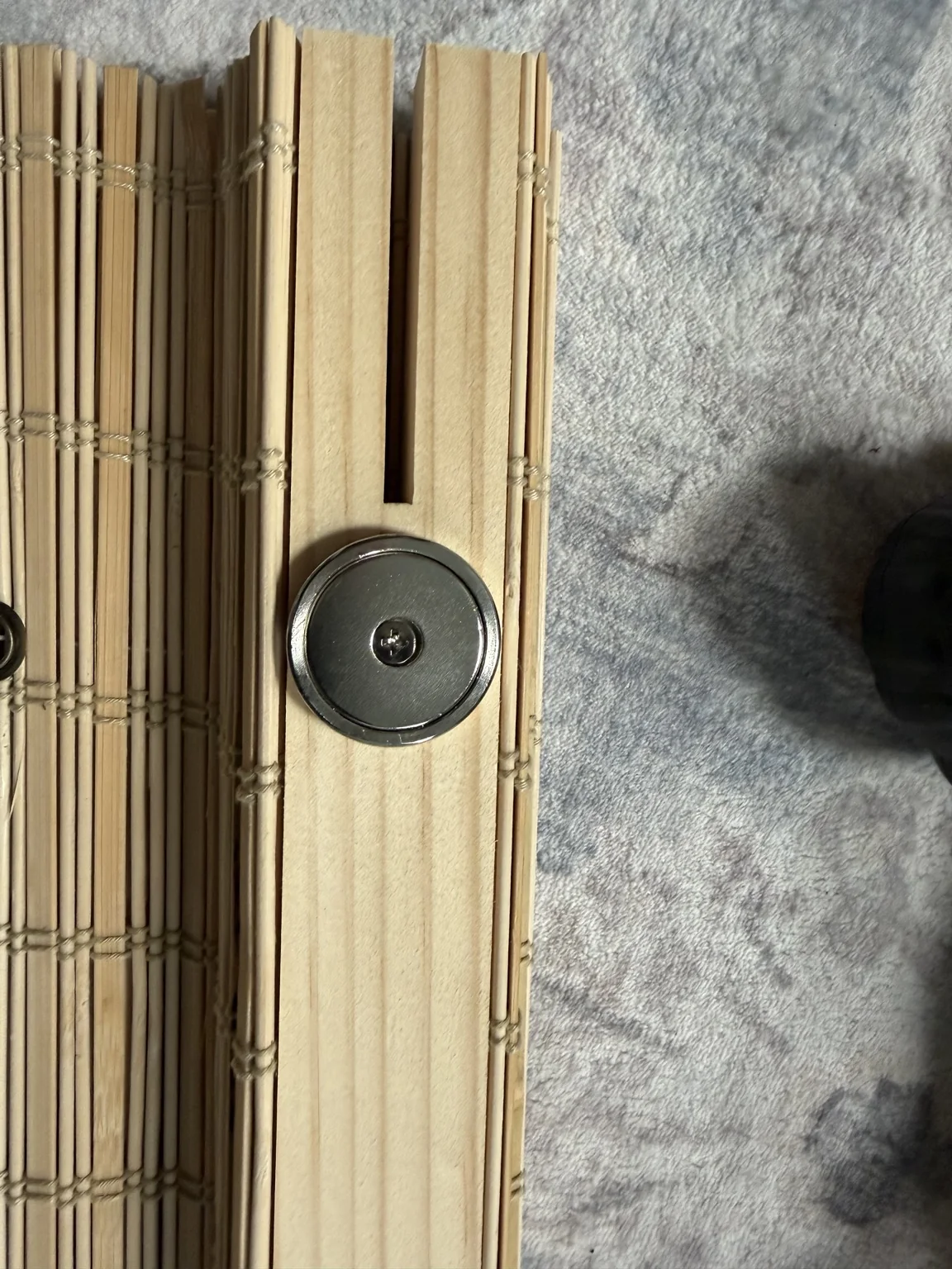 Close-up of round magnet screwed into the wooden header with a flush seated screw