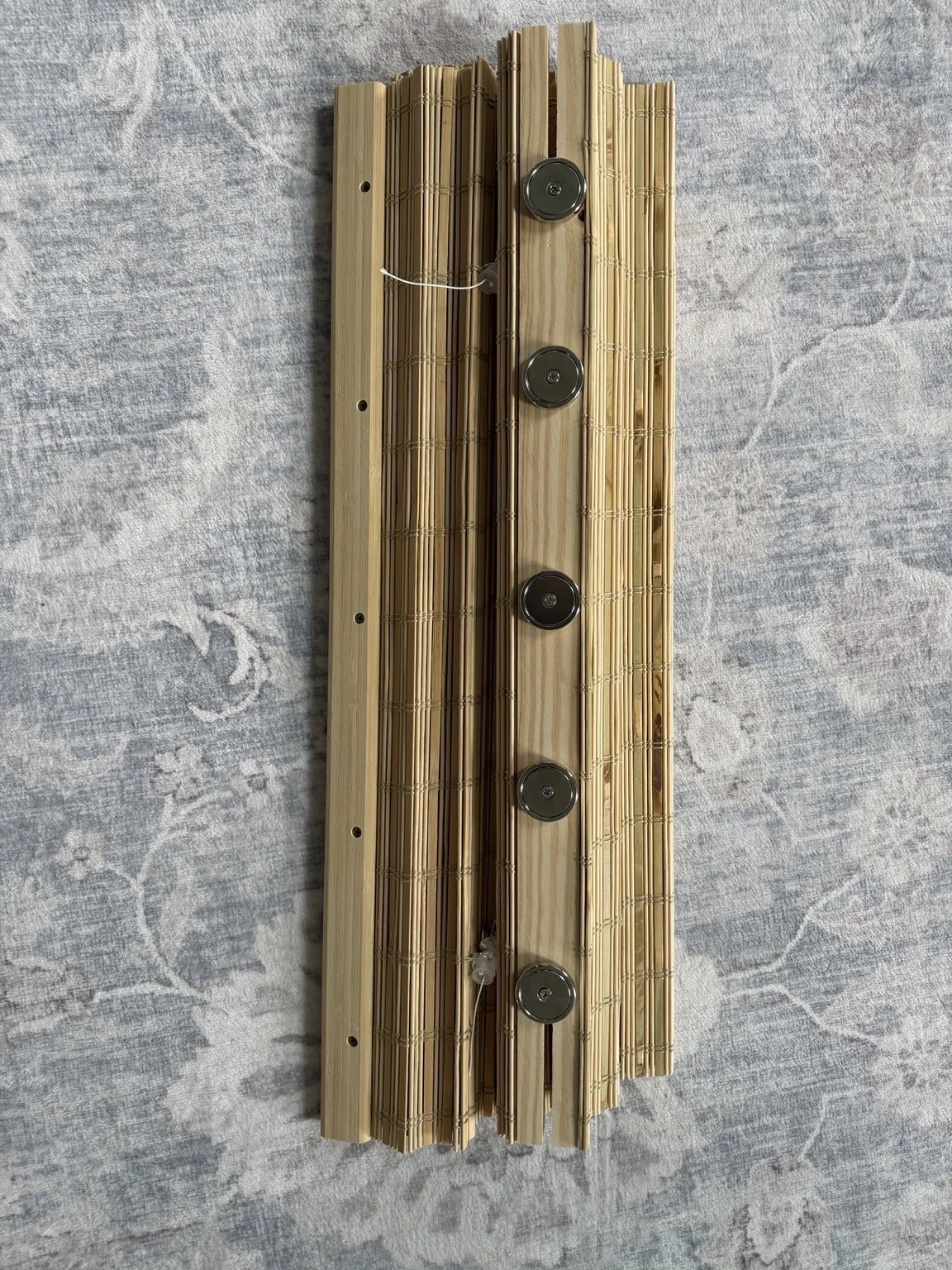 Back of the bamboo shade wooden header showing three round magnets attached along its length